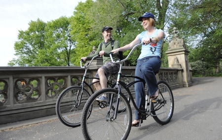 A man and a woman ride bikes along a path in the city