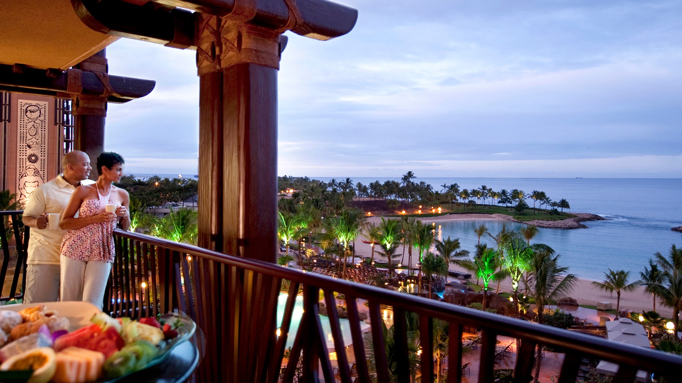 A man and woman on a villa balcony, gazing at the ocean