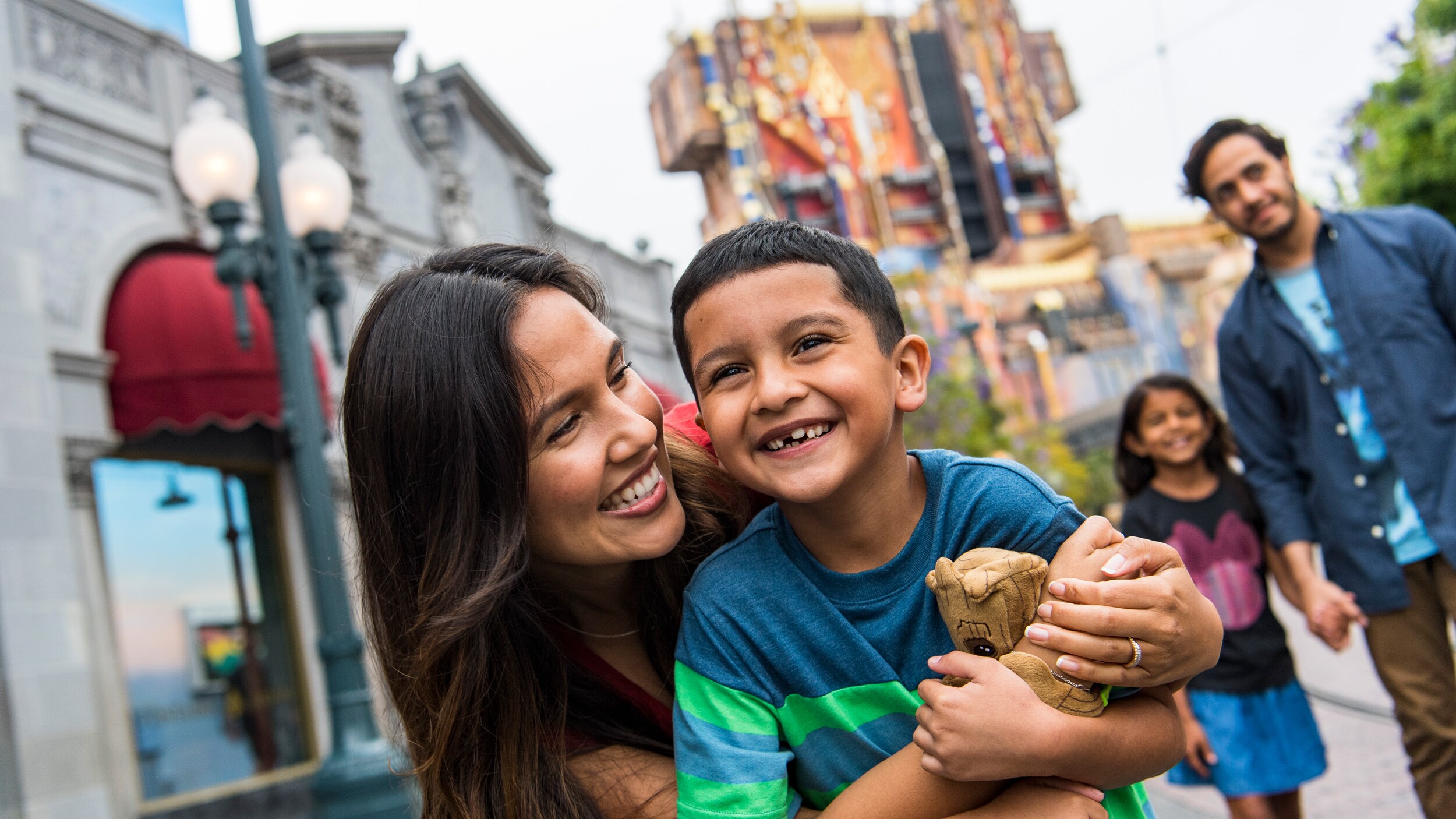 A mother, father, son and daughter walking outside at a theme park